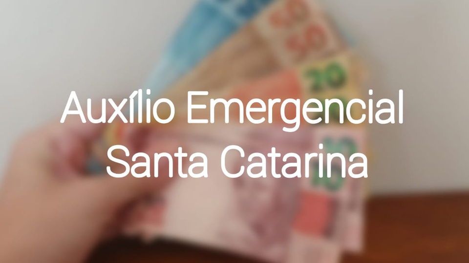 auxílio emergencial santa catarina: imagem desfocada de mão segurando notas de dinheiro